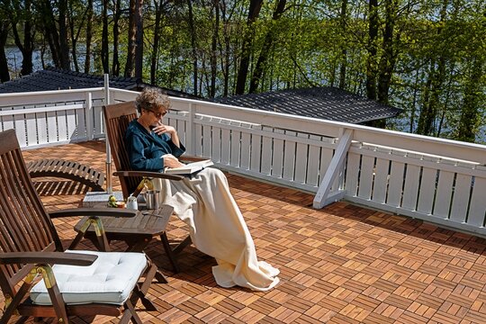 erkner, deutschland - eine frau liest ein buch auf dem balkon