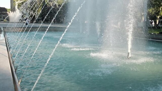 Multiple high-pressure nozzles shooting powerful streams of fresh water into the air at a public city park fountain. Summer heat, urban architecture, municipal engineering, public parks in summer.