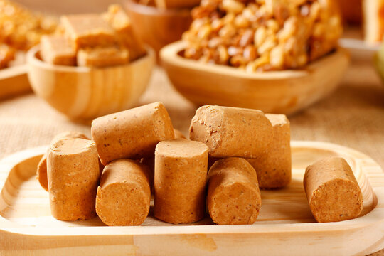 Homemade Brazilian pacoquinha or pacoca, peanut candy, on a bamboo tray, set on a table featuring traditional Brazilian foods.