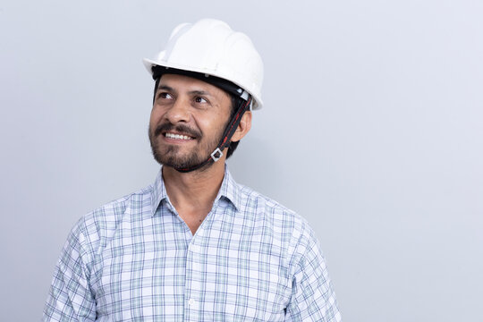 Portrait of confident young male construction engineer in hardhat over formal shirt looking other side while isolated on studio background	