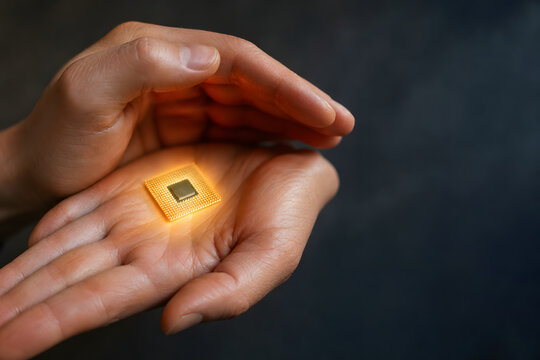 Protective hands shelter glowing microchip in warm light