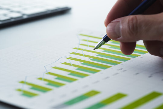 Business report and financial data analysis. Performance analytics with statistical graphs and charts. Businessman reviewing plan and making strategy on desk.