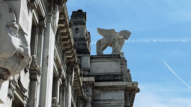 Milano Centrale Grandeur: Sculpted Faces & Winged Horses Against Sky