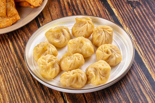 Plate of steamed Asian dumplings momo on rustic dark wood background