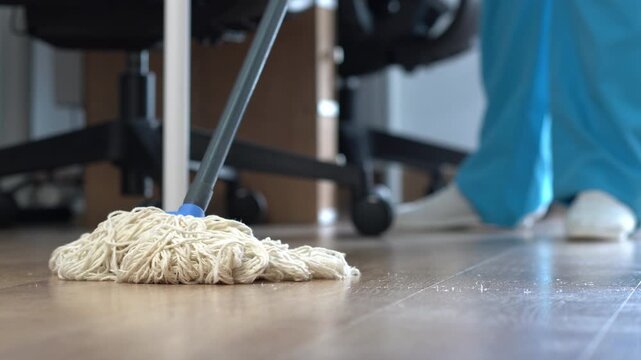 Worker cleans the office with a wet mop