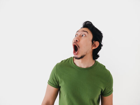Surprised and shocked face Asian man in green t-shirt isolated on white.