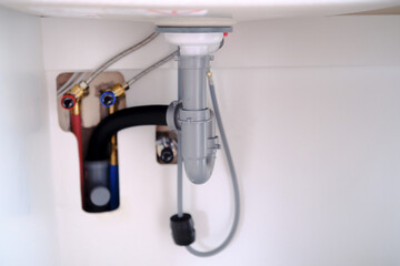 Under sink plumbing with water supply lines and drain pipe © reddish