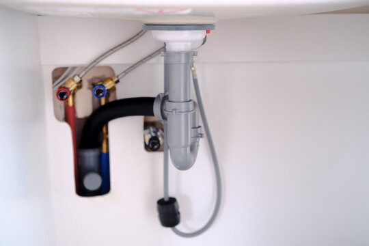 Under sink plumbing with water supply lines and drain pipe