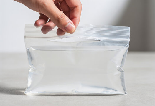 Hand sealing clear zipper bag on light kitchen counter in bright natural daylight and clean lifestyle style