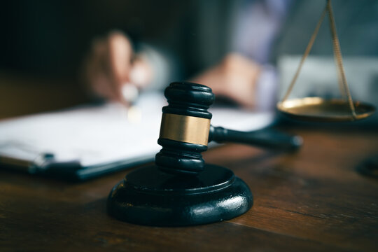 Judge's gavel and scales of justice with a lawyer reviewing documents, symbolizing law, justice, legal services, and court proceedings.