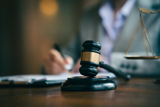 Judge's gavel and scales of justice with a lawyer reviewing documents, symbolizing law, justice, legal services, and court proceedings.