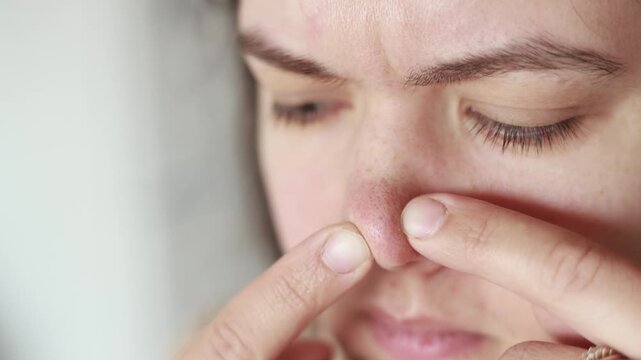 Caucasian woman touches nose with fingers showing blackheads and sebaceous filaments. Close up in slow motion. Problem skin and neglected nails reveal poor self care.