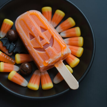 halloween themed ice cream popsicle with candy corn and bat shaped chocolate in black bowl