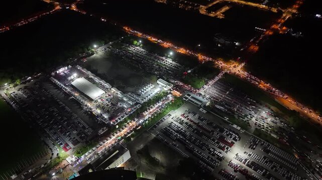 Night aerial footage of Batu Kawan Modifighter automotive and motorsport festival with cars, tents, parking areas.