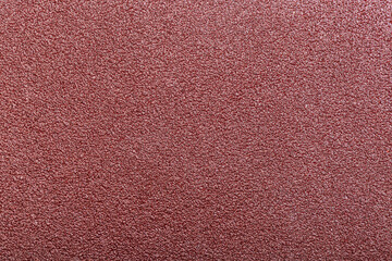 Fototapeta premium Red abrasive sandpaper belt texture with dense grit and rough uneven surface detail