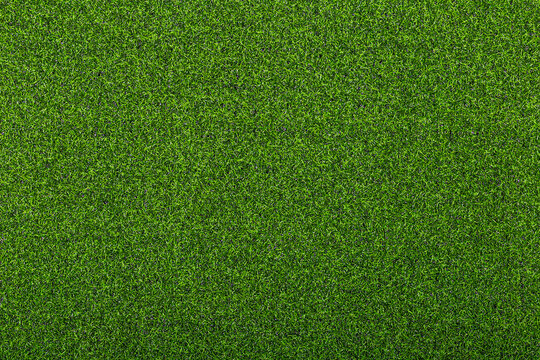 Artificial soccer turf texture with dense green synthetic grass blades in close up view. Sports background for soccer field, training ground, playground, and outdoor design.