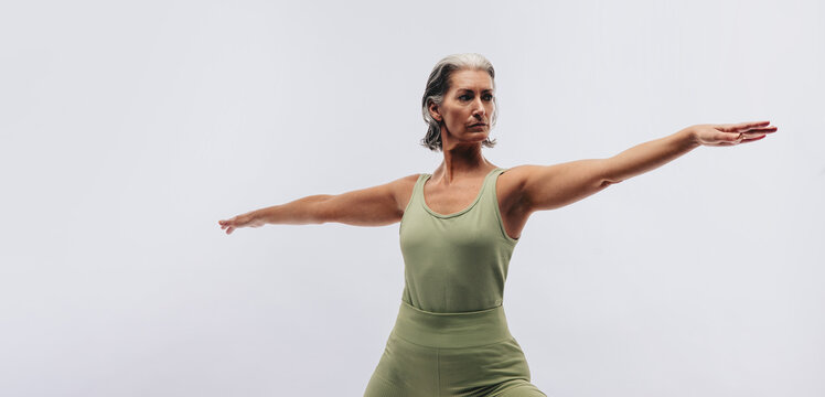 Woman holding warrior II yoga pose in studio
