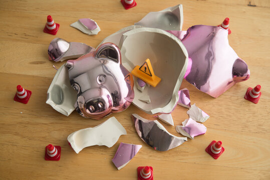 Broken piggy bank with yellow warning sign inside. No savings, poor due to many expenses, high cost of living, inflation, global economy crisis, unemployed, loss investment and so on concept.
