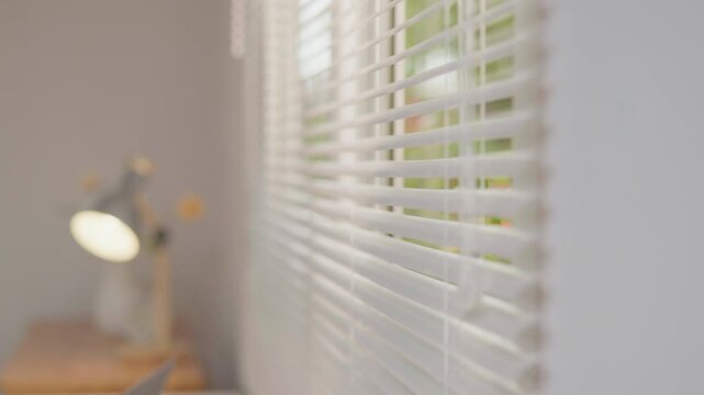 Soft focus home office interior with window blinds and desk lamp, ideal for background, copy space, workspace, natural light and modern home concepts.