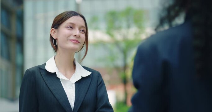 Young Businesswoman Smiling and Shaking Hands with Colleague Outside Modern Office Building, Professional Business Meeting and Partnership Concept