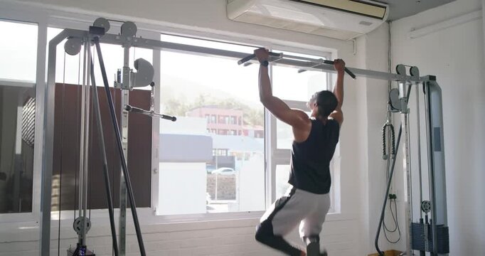 African American male in tank top entering gym training kipping pullups touching window gazing out