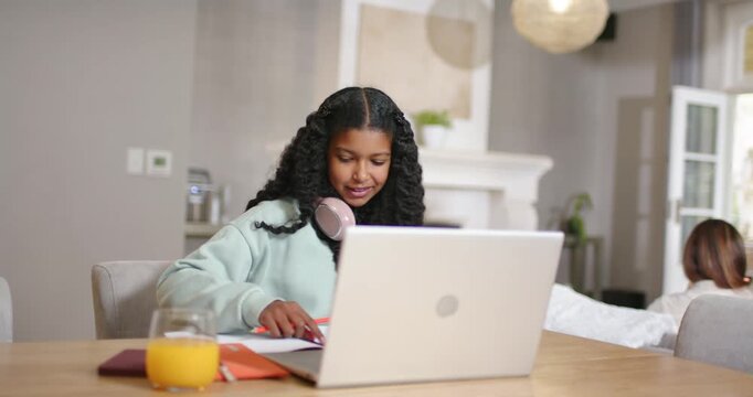 African American family on online call, teenage daughter waving, noting on laptop at home for class