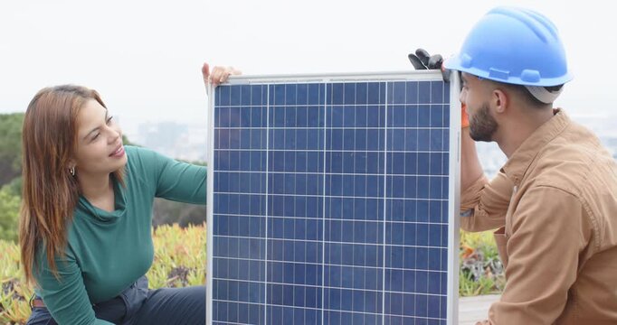 African American technician and client aligning solar panel on roof after lifting to mount, gloves