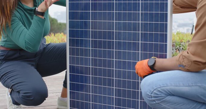 African American colleagues steadying panel with orange gloves while inspecting cell grid on deck