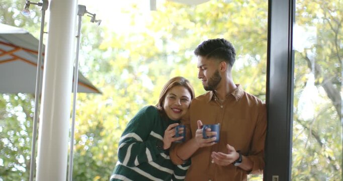 African American couple standing in doorway sharing morning coffee, linking arms, sipping blue mugs