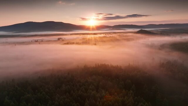 Sunrise through fog over mountainous landscape