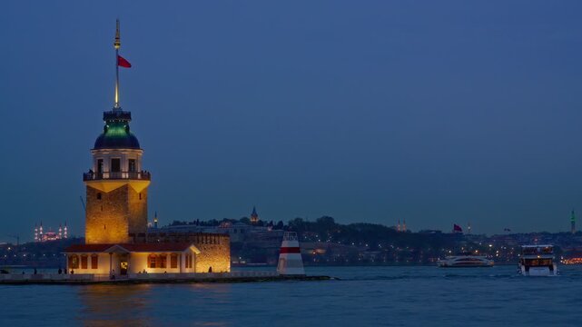 The iconic Maiden's Tower illuminated against a deep blue twilight sky in the middle of the Bosphorus sea in Istanbul with city lights in the background