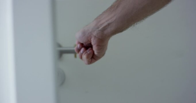 Close up of a hand using a brass hygiene tool to press buttons on a wall remote control panel