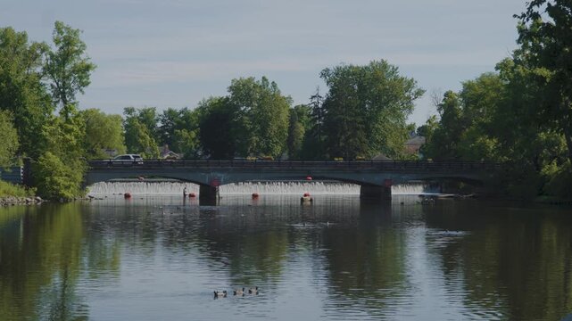 Wide shot of a small bridge and dam on a sunny day. 