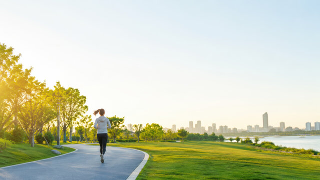 Woman jogging through green park path at warm golden hour
