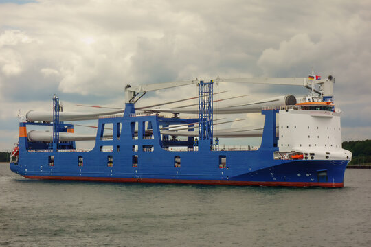 Heavy Lift Cargo Ship Transporting Wind Turbine Blades at Harbor Under Dramatic Storm Clouds, Renewable Energy Logistics