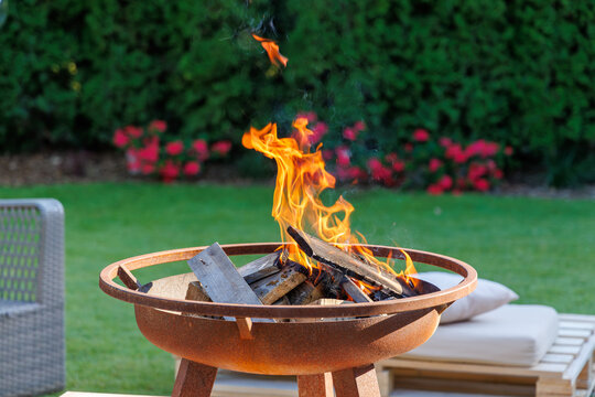 Cozy Outdoor Fire Pit Burning with Bright Flames in Backyard Garden, Relaxing Evening Patio Ambience and Outdoor Living Concept