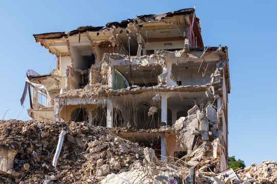 Collapsed multi-story building with rubble and exposed concrete after earthquake or war destruction, disaster concept