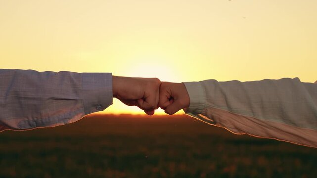Man, woman greet each other with fist bump. Fist bump sign agreement, gesture respect. Close-up business team fists. Trust, understanding, teamwork. Fists against sky sun, trust, harmony, friendship