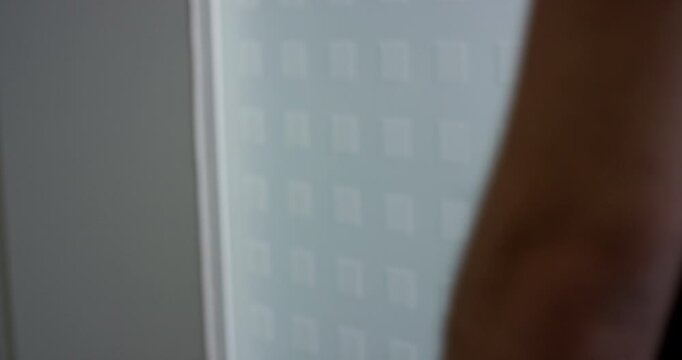 Close up of a hand using a brass touchless safety hook to open a glass office door