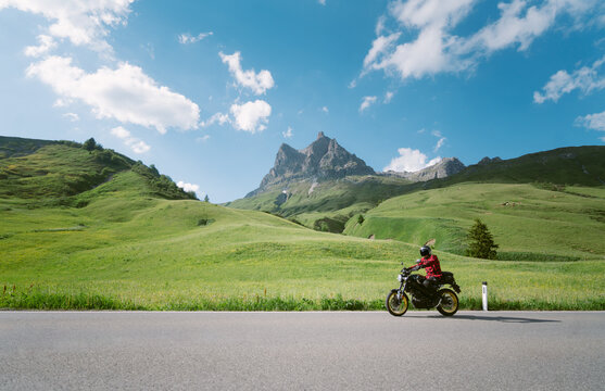 Motorcyclist riding on alpine mounain road in the Alps in summer