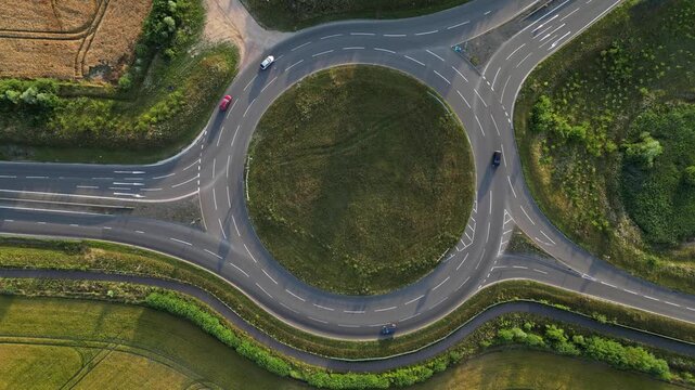 Aerial drone footage of cars moving around a large rural roundabout on the NDR bypass road near Norwich, Norfolk, England. Modern UK road infrastructure, traffic flow, transport and countryside roads