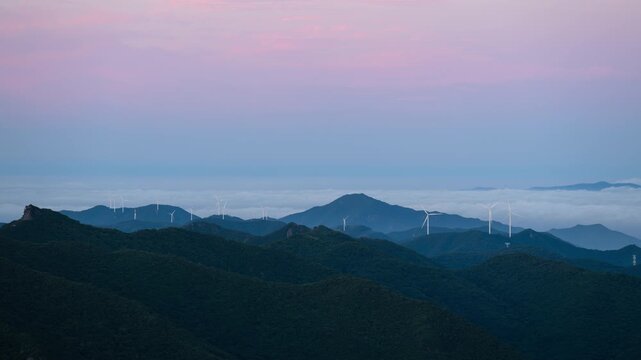 Timelapse of a Wind Turbine Farm on a Forested Mountain Ridge at Sunrise. Wind turbines generate clean renewable energy.	
