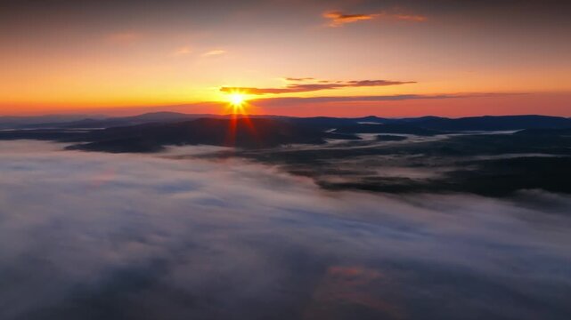 Sunrise with sun above foggy mountain landscape