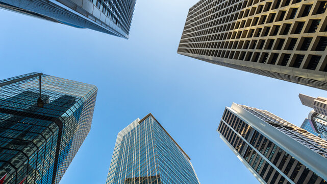 Low angle view of modern skyscrapers against clear blue sky in financial district, showcasing urban architecture, business growth, corporate environment and future city development concept