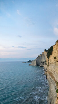 A serene and majestic view of the golden cliffs at Logas Beach in Corfu, evoking a deep sense of peaceful isolation, romantic wanderlust, and the calming beauty of a Mediterranean sunset escape.