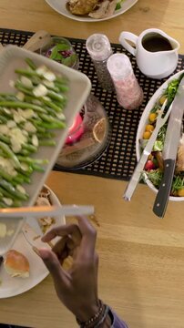 Vertical video: Reaching plate, two hands in cream sweater and plaid sleeve serving food at table