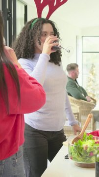 Vertical video: Toasting curly woman in top with antlers chopping salad at home for meal with bowl