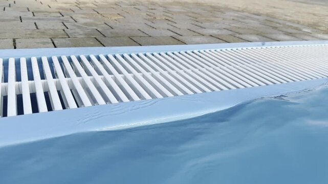 Swimming pool edge with drain grate and blue water