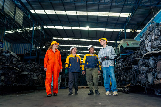 Diverse people team of industrial workers meeting and discussion in used car engines warehouse, automotive repair industry teamwork with engineers and technicians in maintenance and recycling factory.