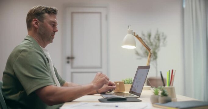 360 Degree. Caucasian Man Working on Laptop Computer at Cozy Home Desk, Browsing Internet, Researching Information and Concentrating on Remote Freelance Tasks in Modern Apartment. Arc Tracking Shot.